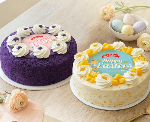 Two Easter-themed cakes on a wooden table with decorative eggs and flowers.