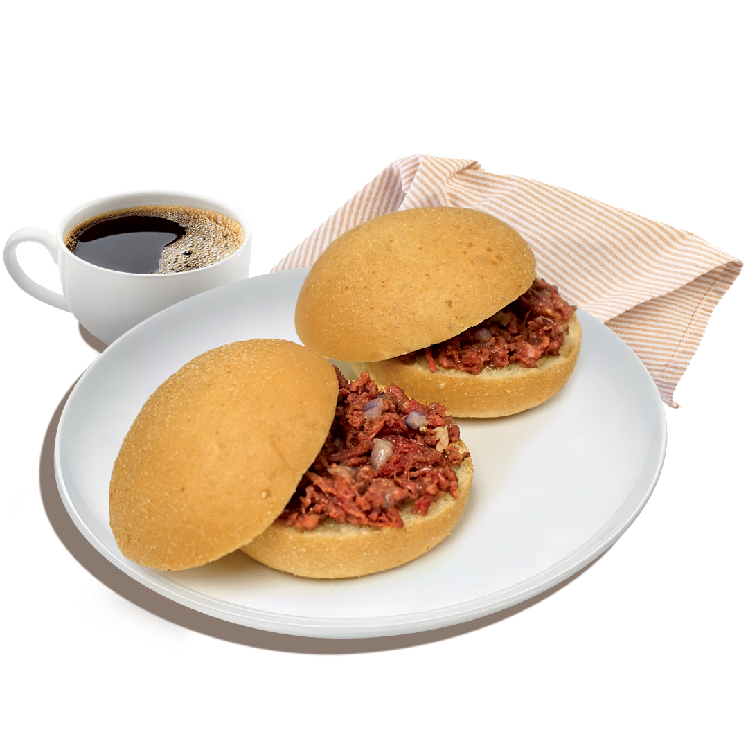 2 pieces of Corned Beef Pan De Sandwich on a plate with a cup of coffee