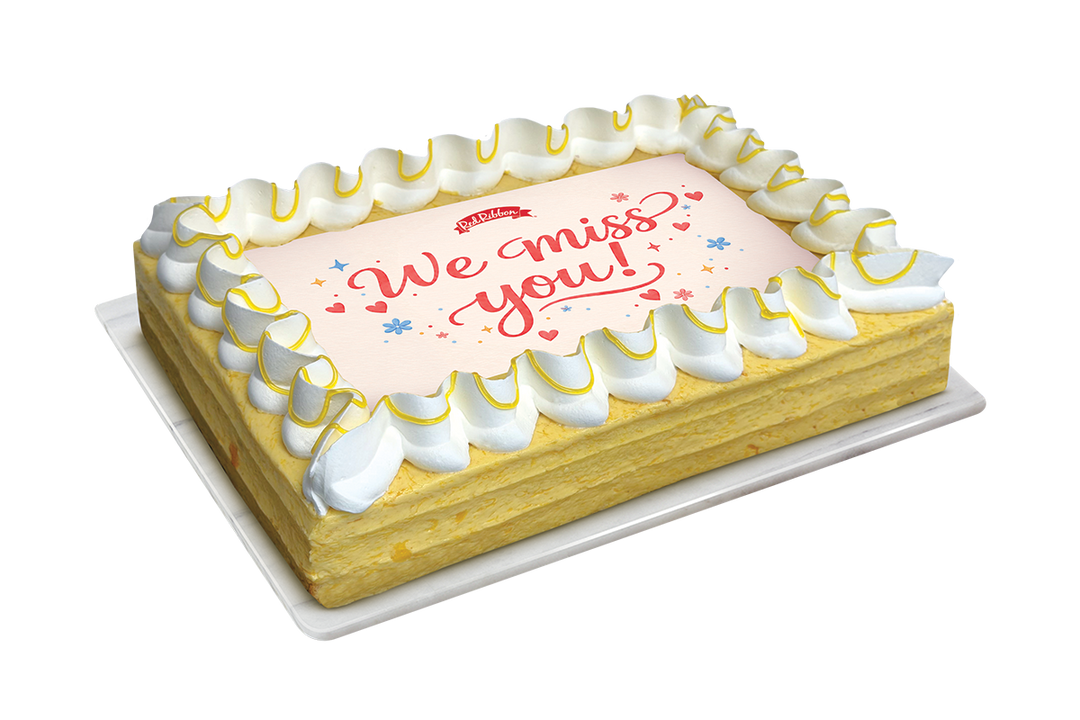 Rectangular cake with We Miss You messaging on top of a mango buttercream cake