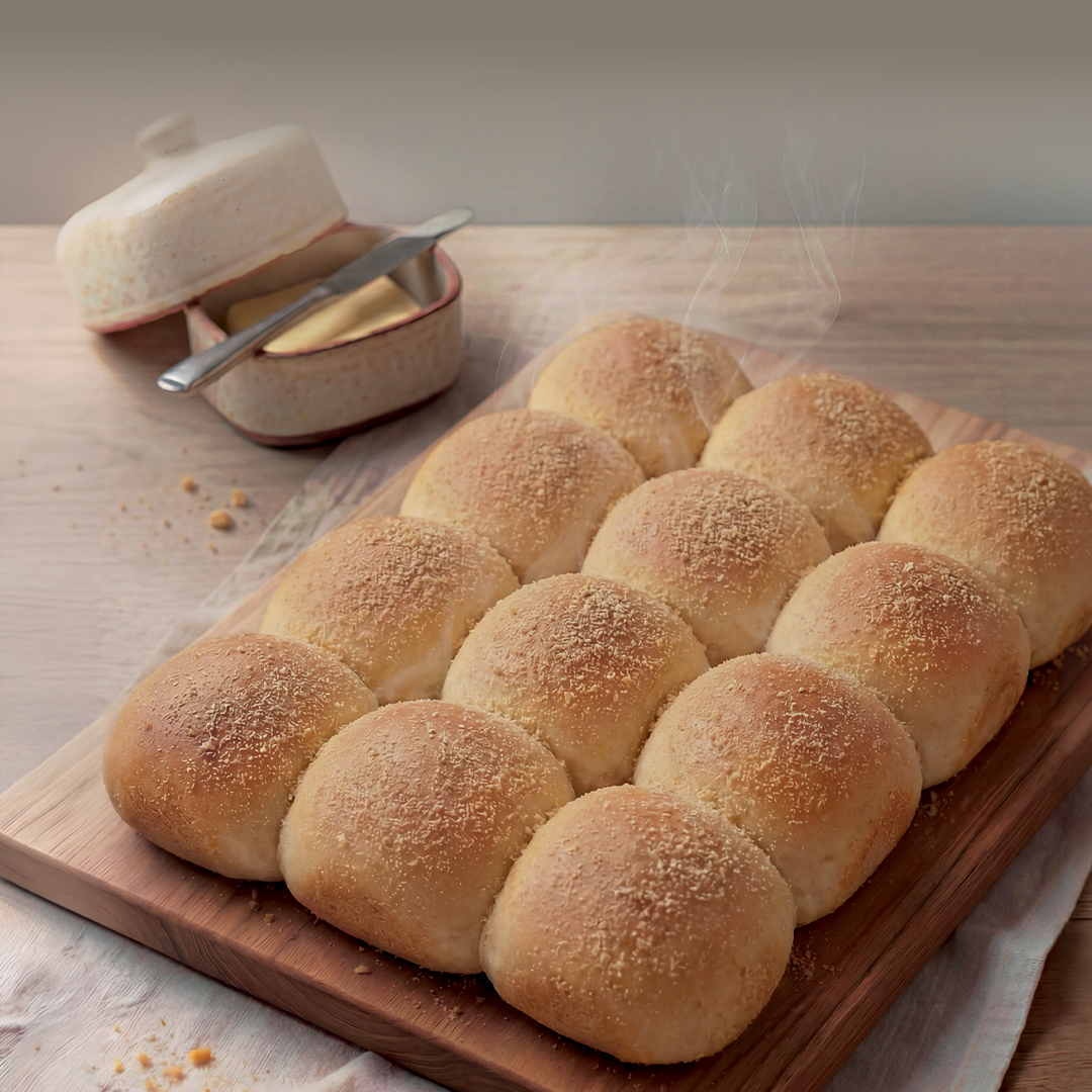 Baked pandesal on a wooden board with a butter dish in the background