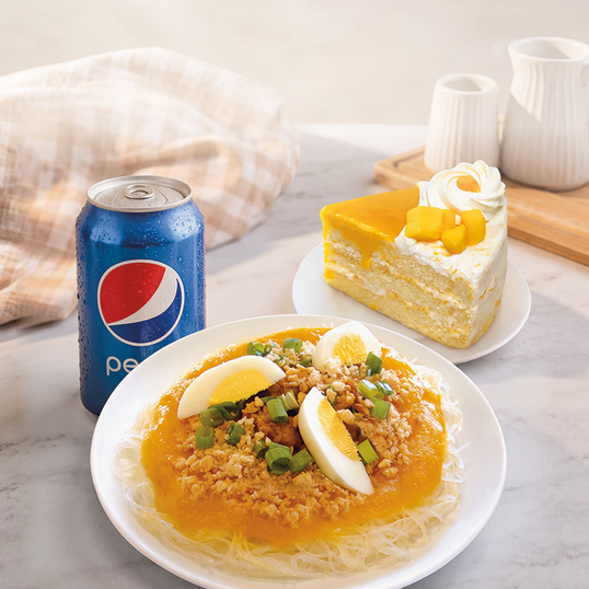 A plated meal featuring  rice noodles, minced meat, green onions, and hard-boiled eggs, served alongside a blue Pepsi can and a slice of layered cake on a marble tabletop.